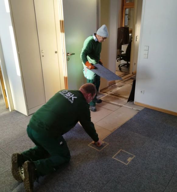 Zwei Mitarbeiter, die den alten Teppichboden entfernen